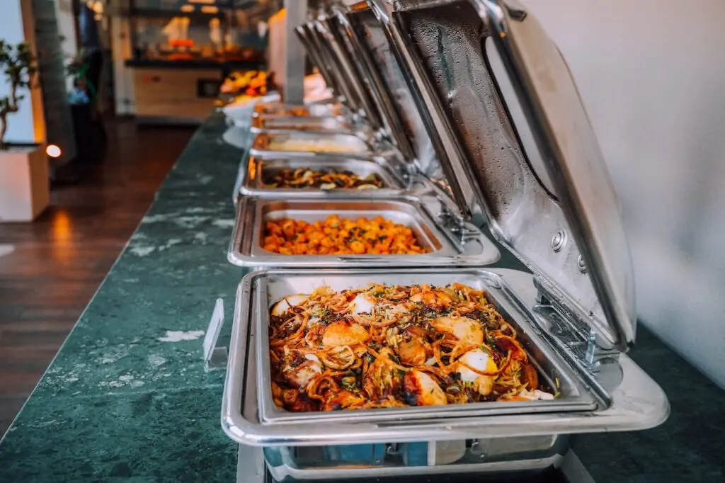 A display of food in buffet style coolers set by caterers at an event.